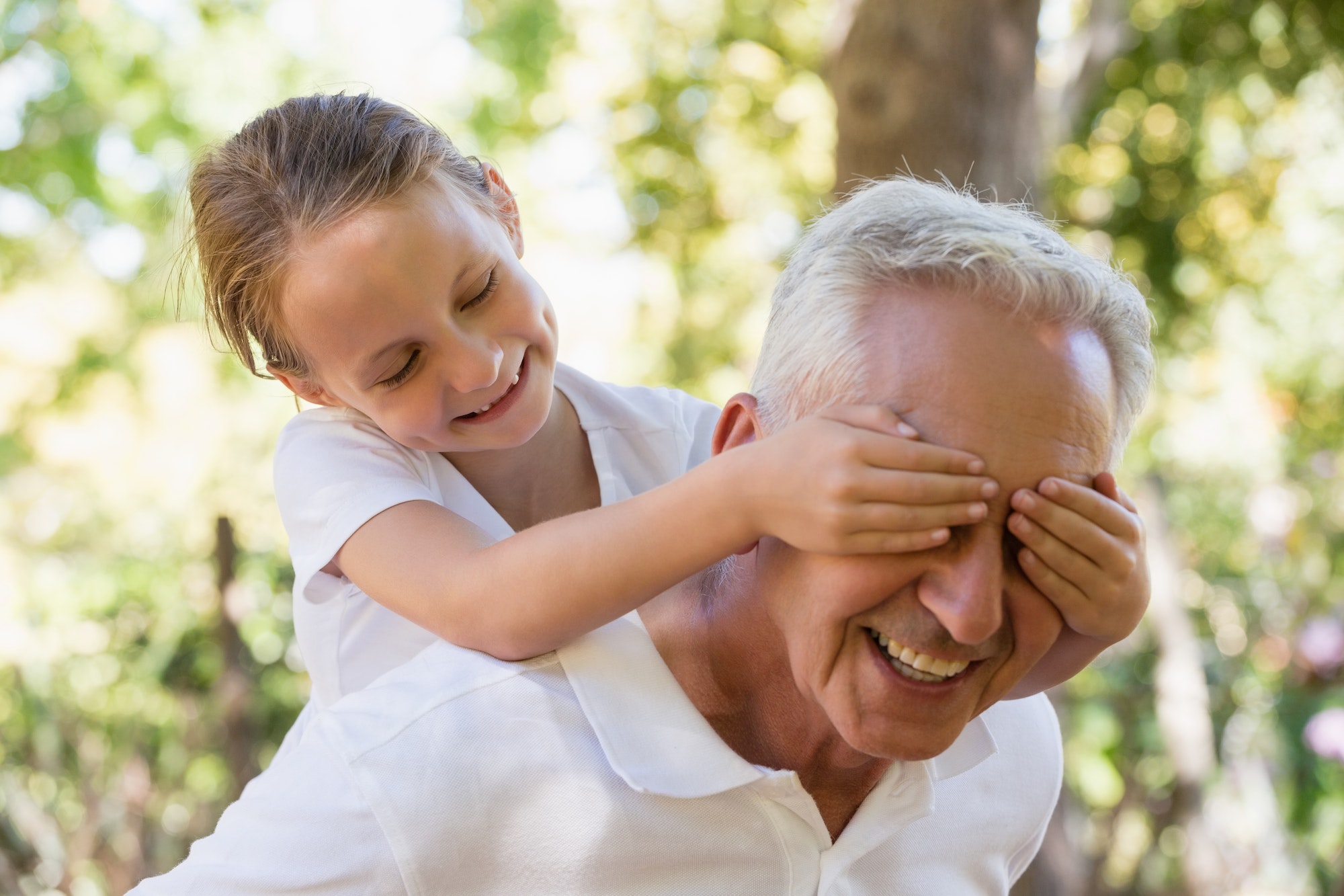 Girl covering his grandpa's eyes in the forest